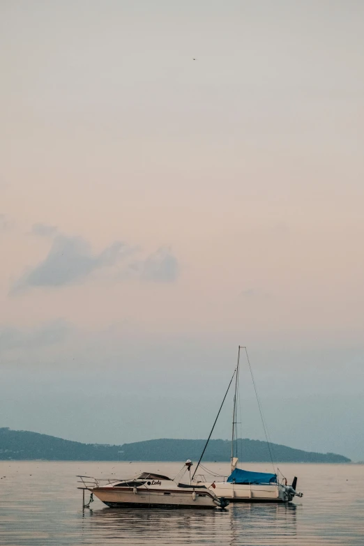 a sailboat with a flag is sitting still in the ocean