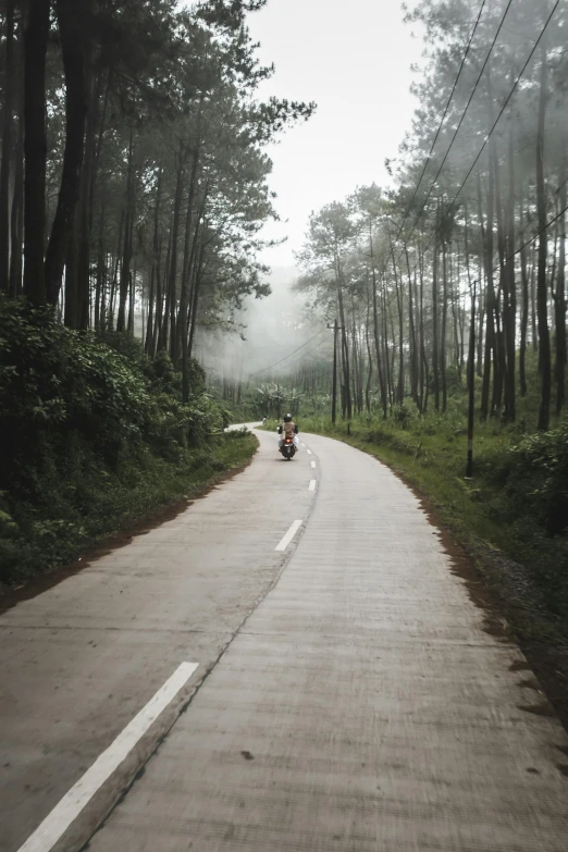 the motorcycle is riding down the narrow road