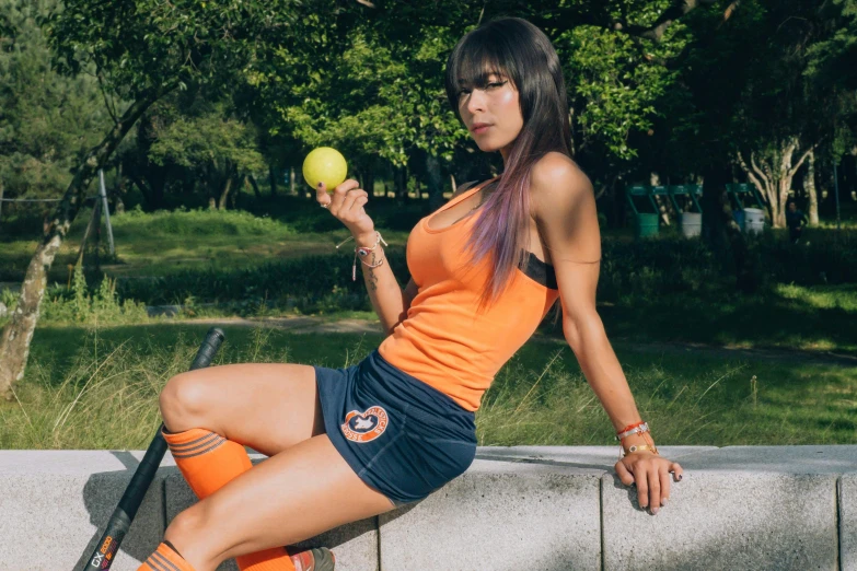 woman wearing orange shirt and blue skirt with racquet on her knee