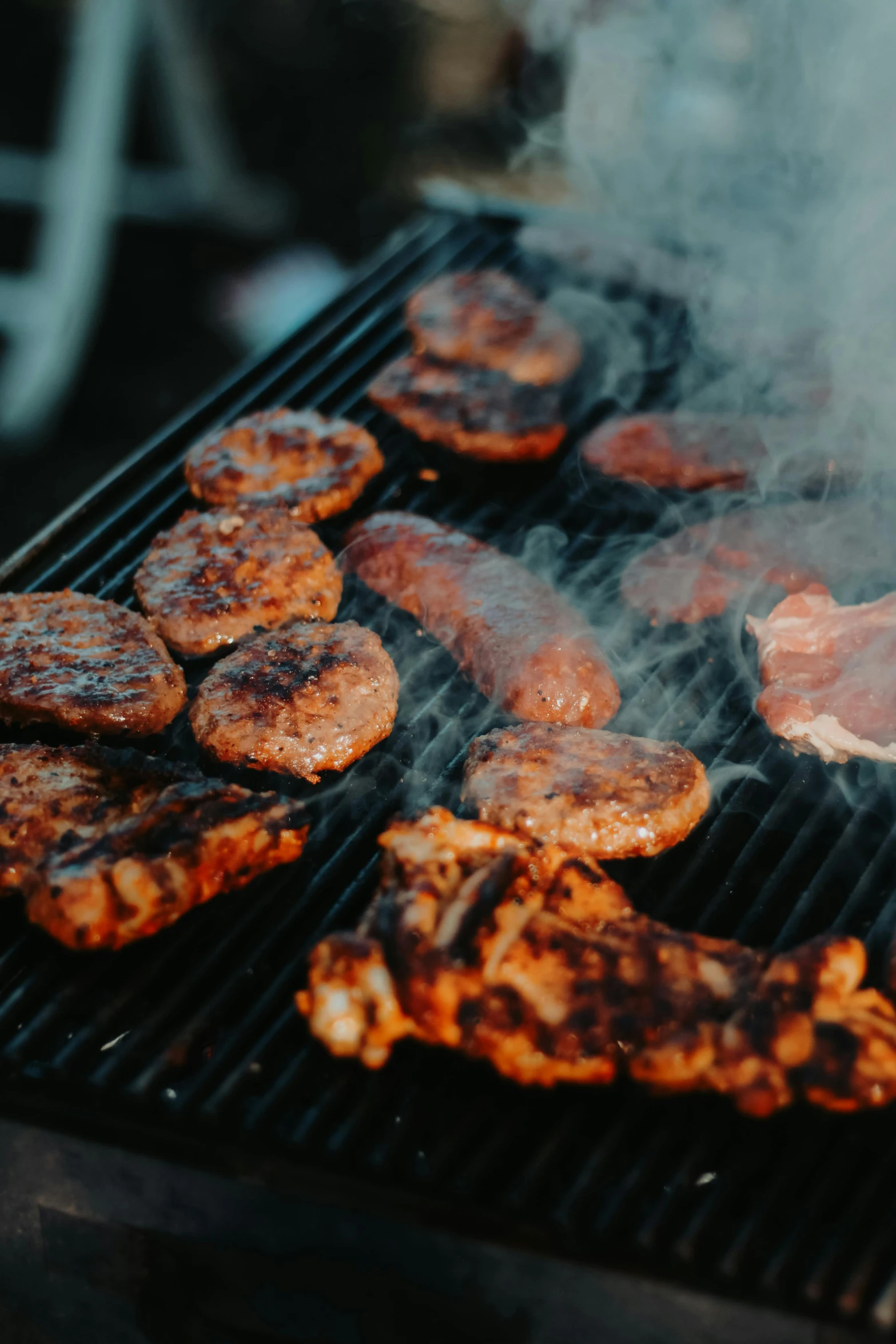 some  dogs and hamburgers cooking on a grill