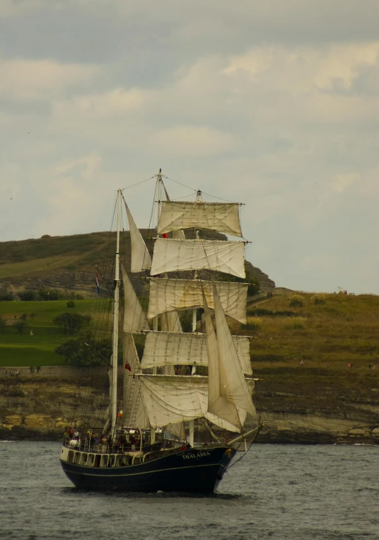 large white sail boat with many sails sailing in the water