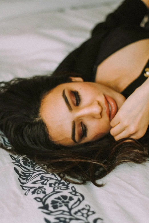 a woman lies on a bed with her head on her hands