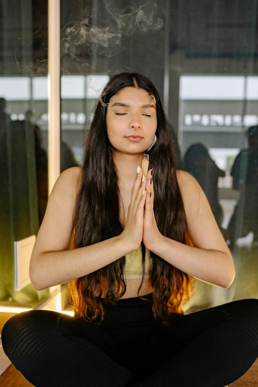 a woman is sitting in a lotus position and holding incense sticks