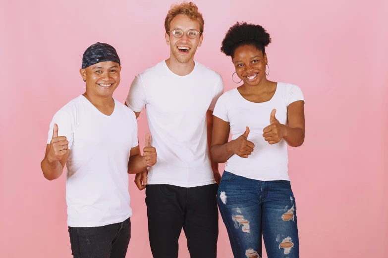 three smiling young people, two with thumbs up