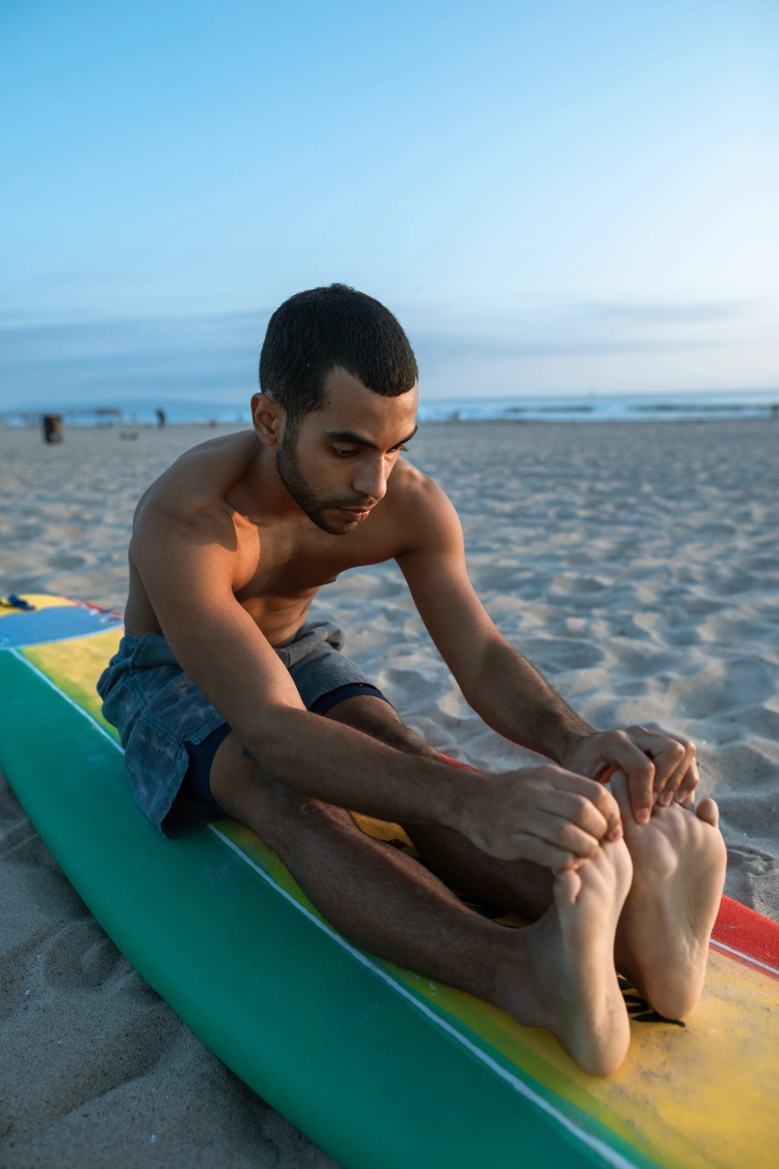 a man on his surfboard holding his feet with the other hand