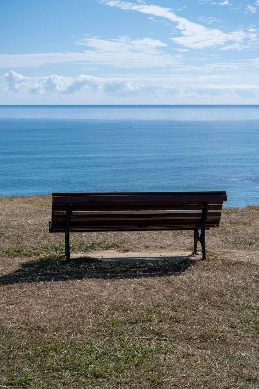 a lone bench sitting in front of an ocean