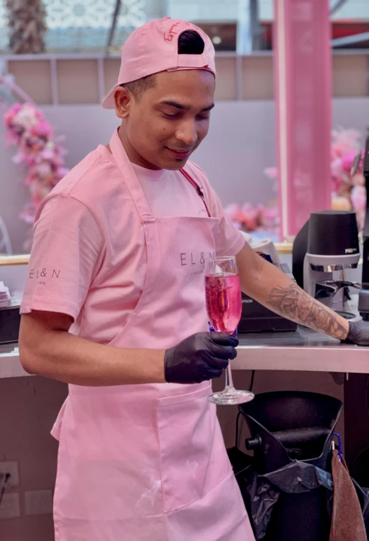 a man in pink apron and head scarf making food in a kitchen