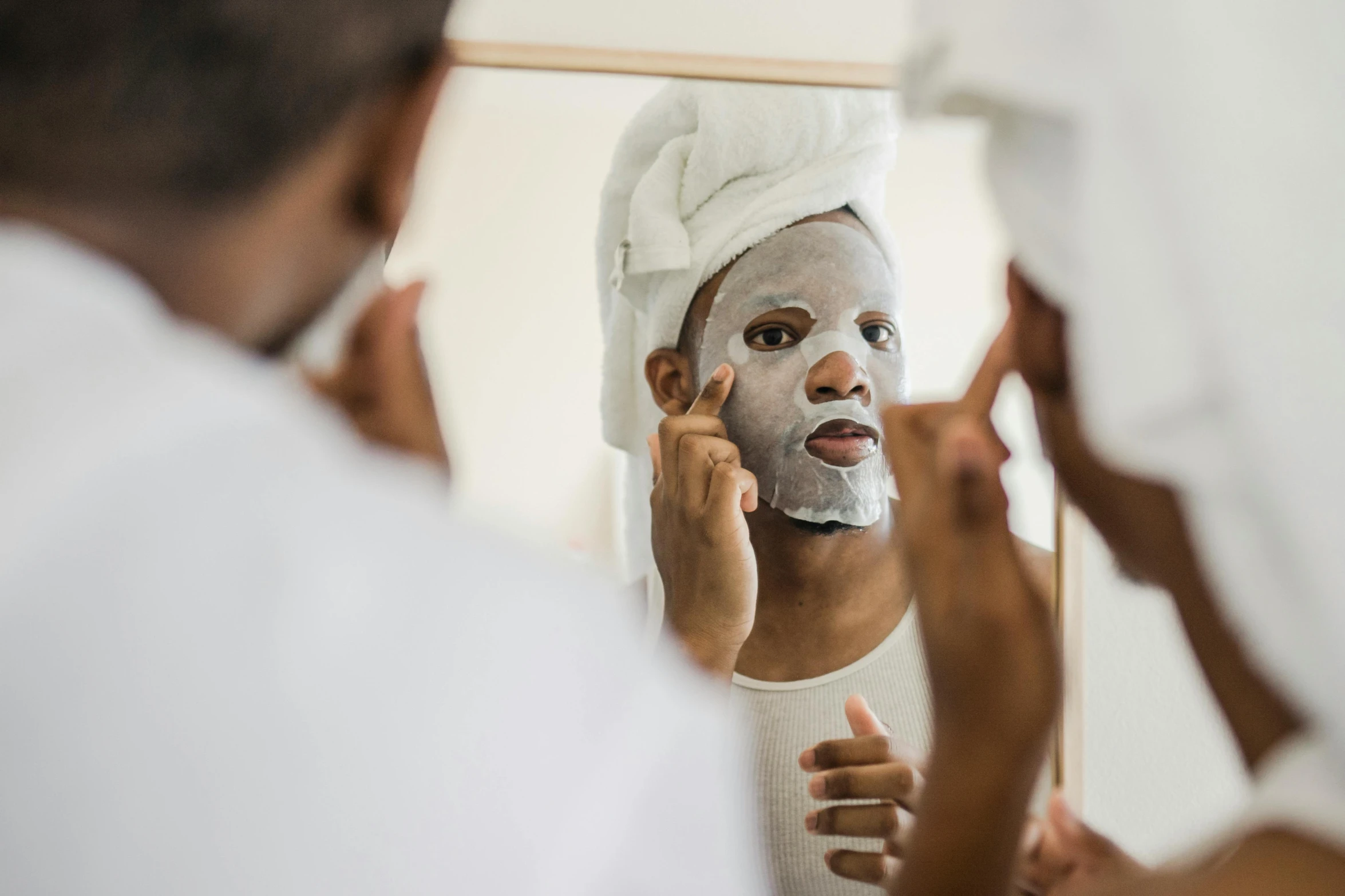 an attractive young woman applying her face with a mask on