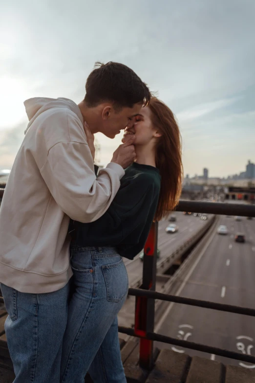 a couple kissing each other next to a highway