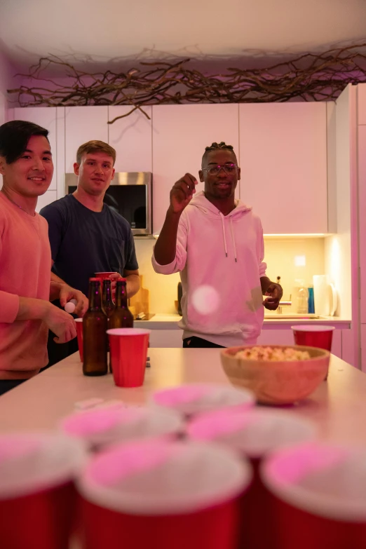 four guys in a kitchen smiling and waving