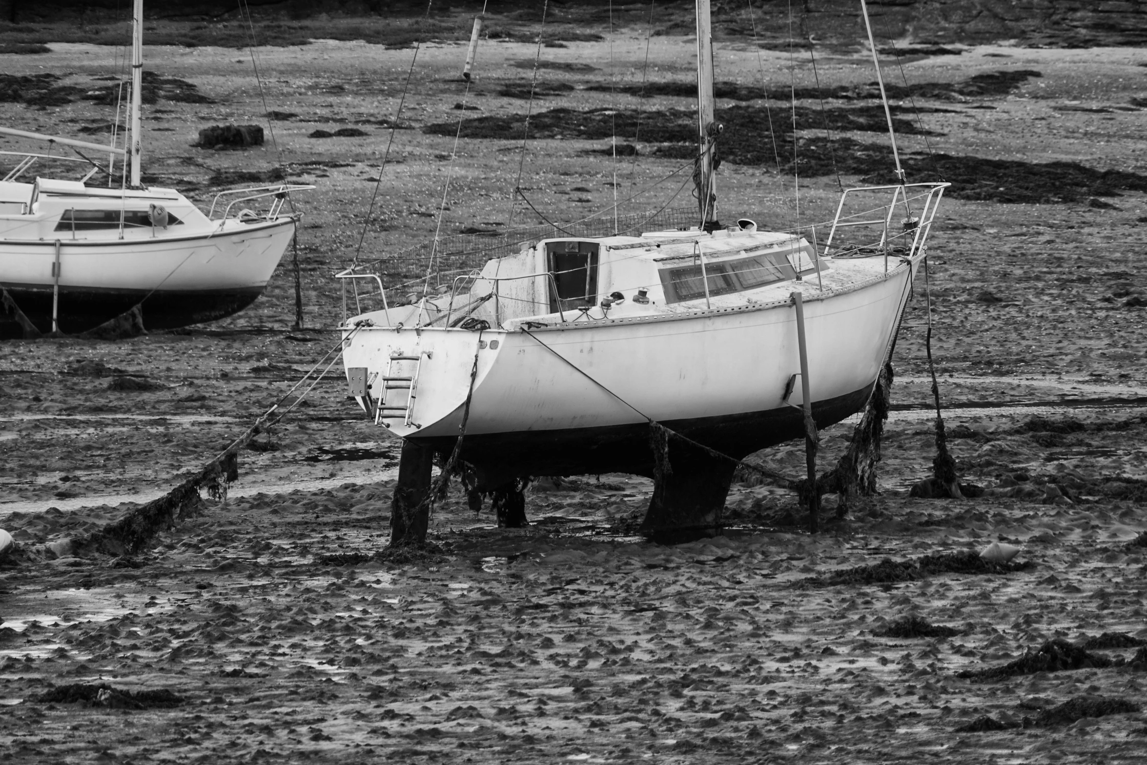 two white boats are parked on the dirt