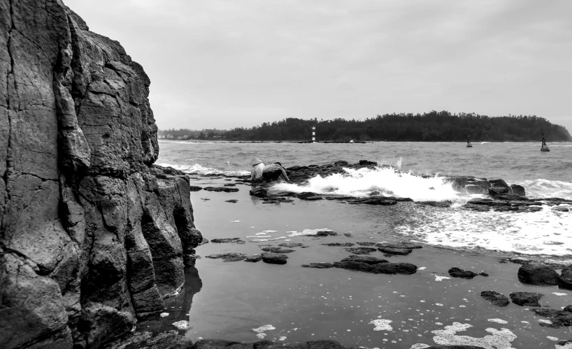 a small sailboat traveling past a large rock wall