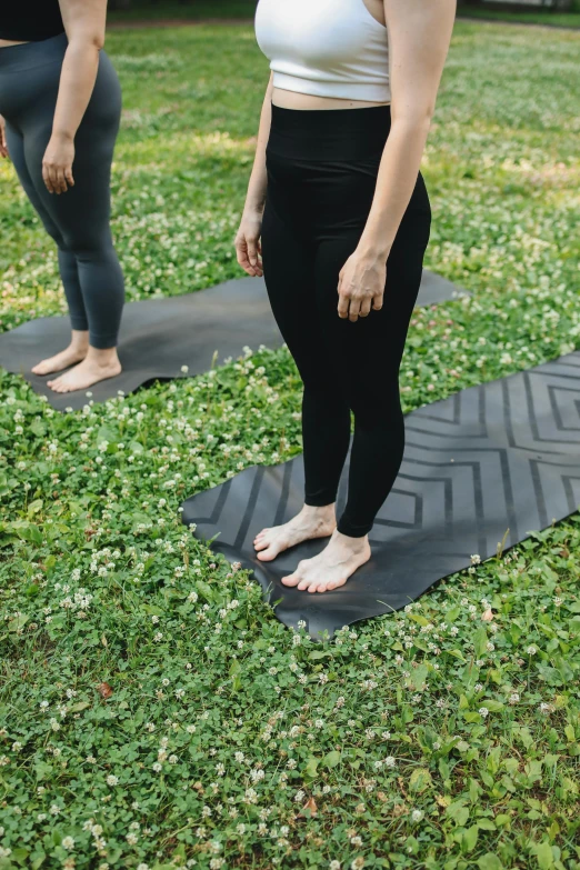 a woman wearing a white tank top and black pants is doing yoga