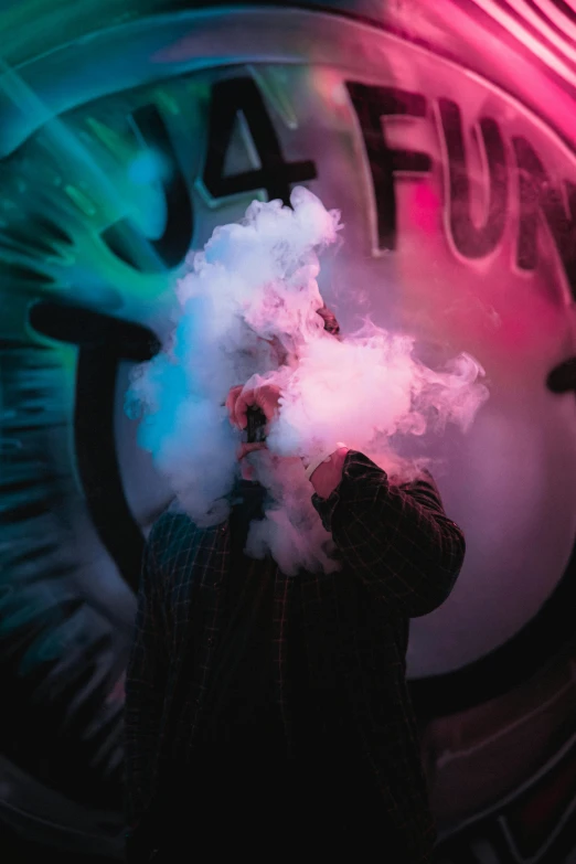 a man is standing in front of a sign and smoking a cloud