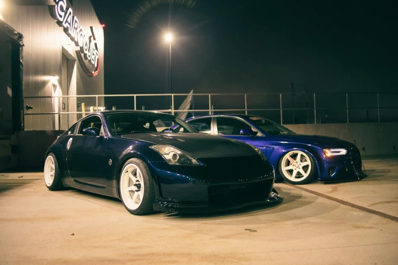 a couple of blue sports cars are parked in front of a shop