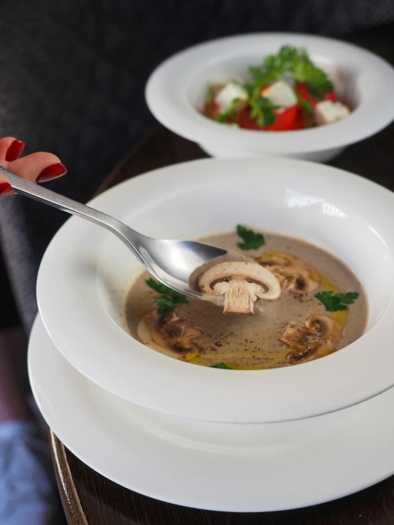 two bowls of food with mushrooms and greens on each one