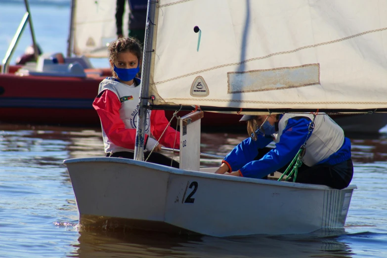 young children are sitting in a small sailboat