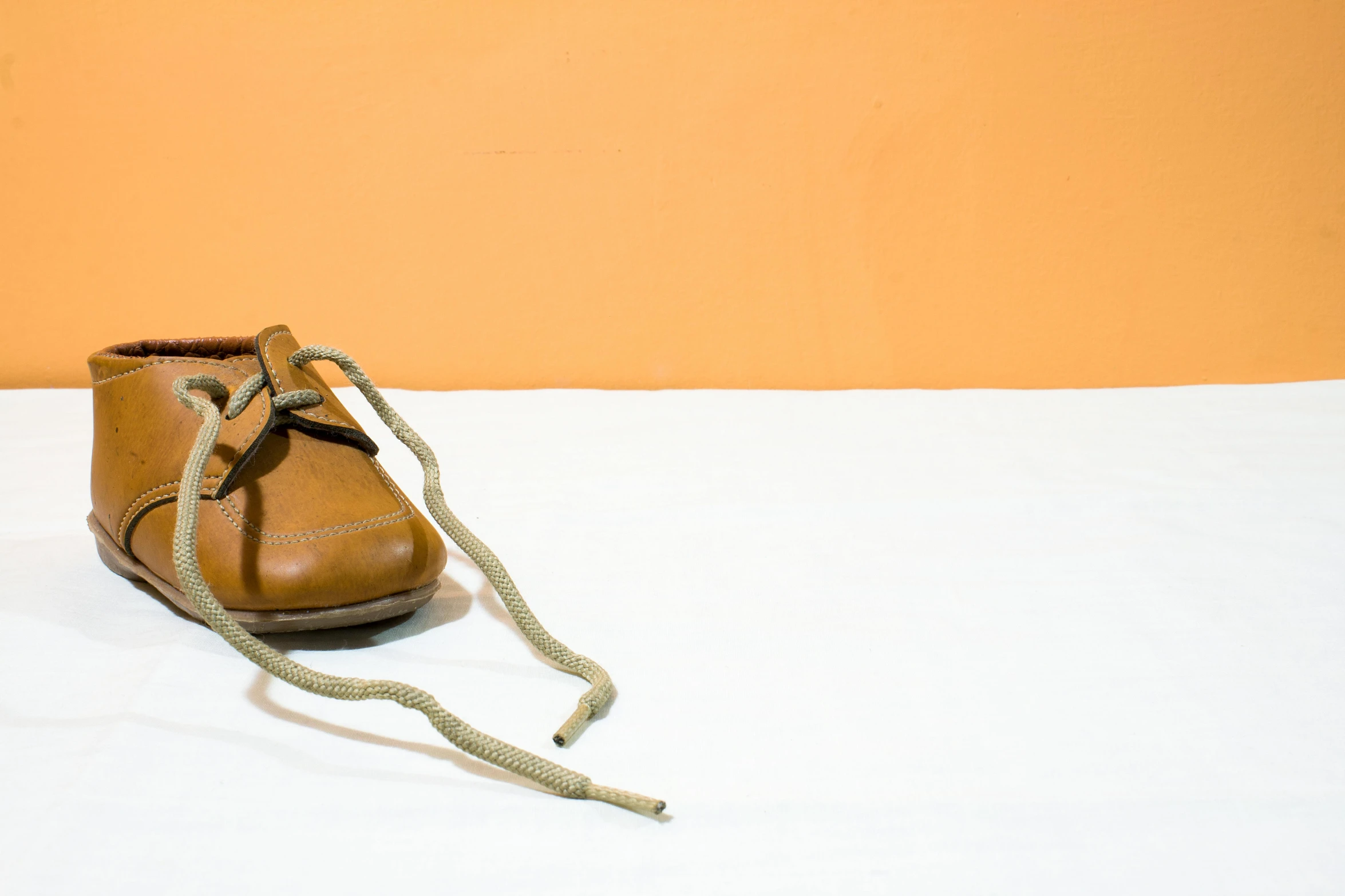 a pair of shoes sits with a rope on a white bed sheet