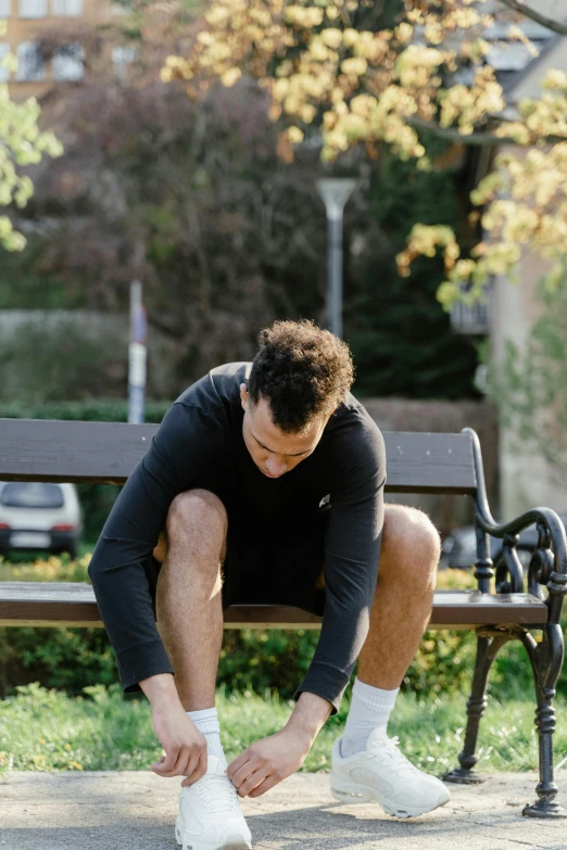 the man in the black sweater is tying his shoes