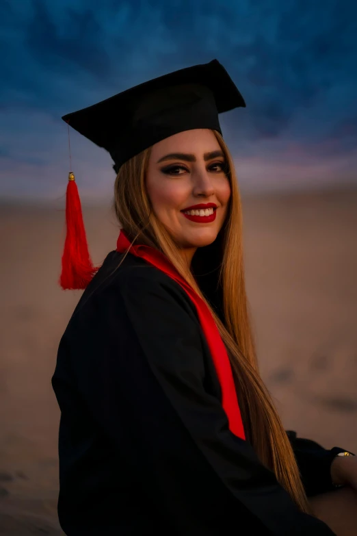 a woman wearing a graduation gown and mortar, poses for the camera