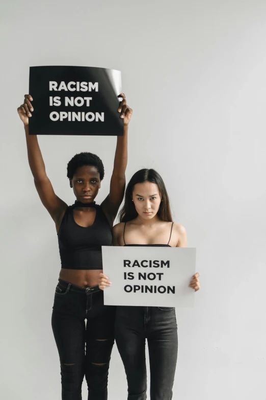 two young women holding signs standing side by side