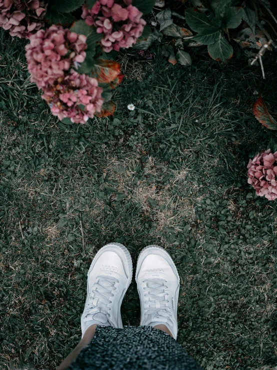 a person wearing white sneakers and white jeans on grass