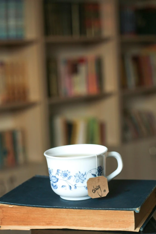 a cup on top of a book in front of a bookshelf