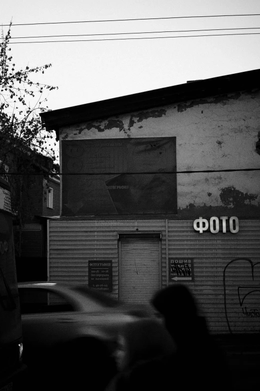people walk past graffiti - covered garage doors in black and white
