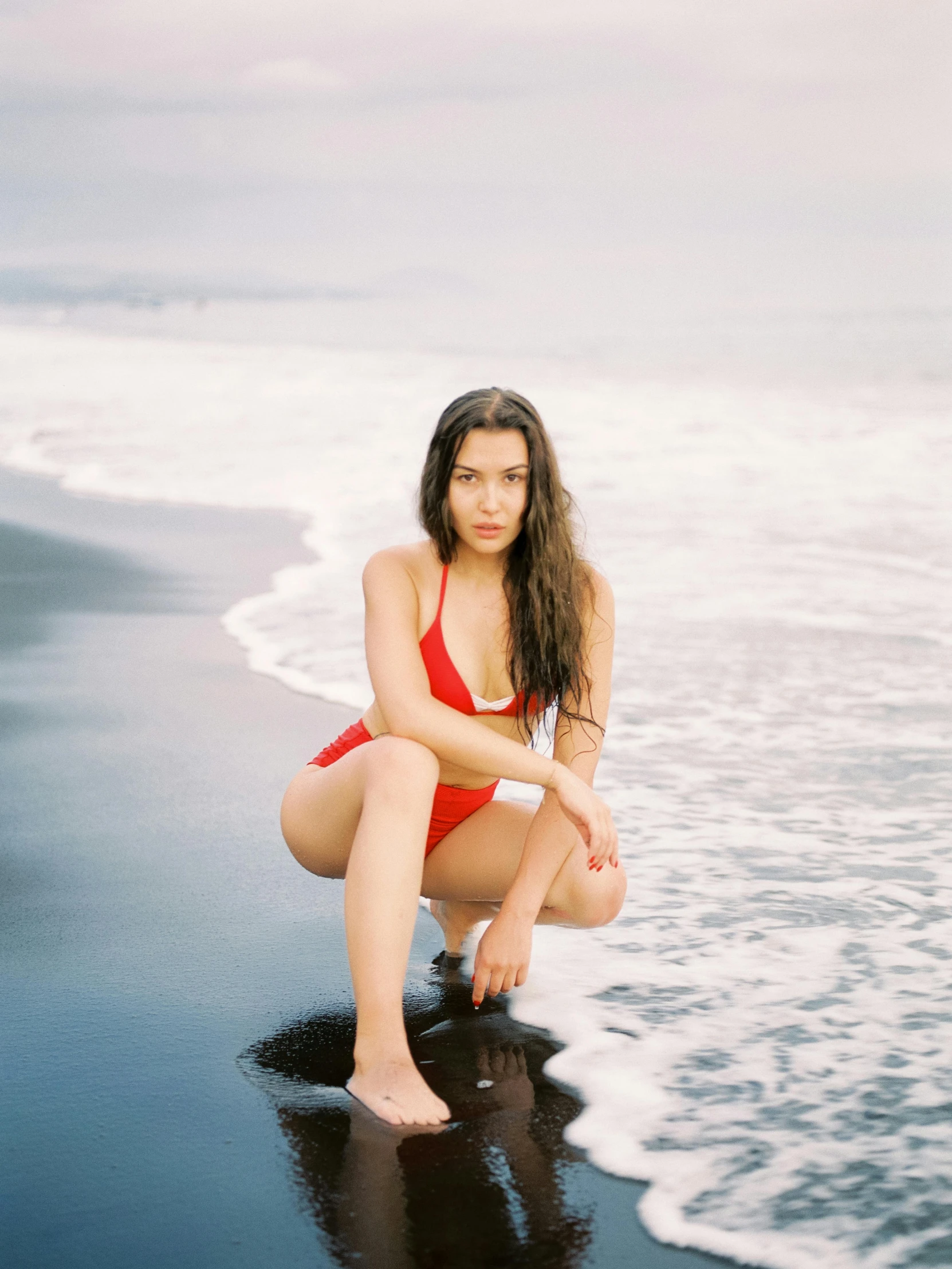 a women who is kneeling down on the beach