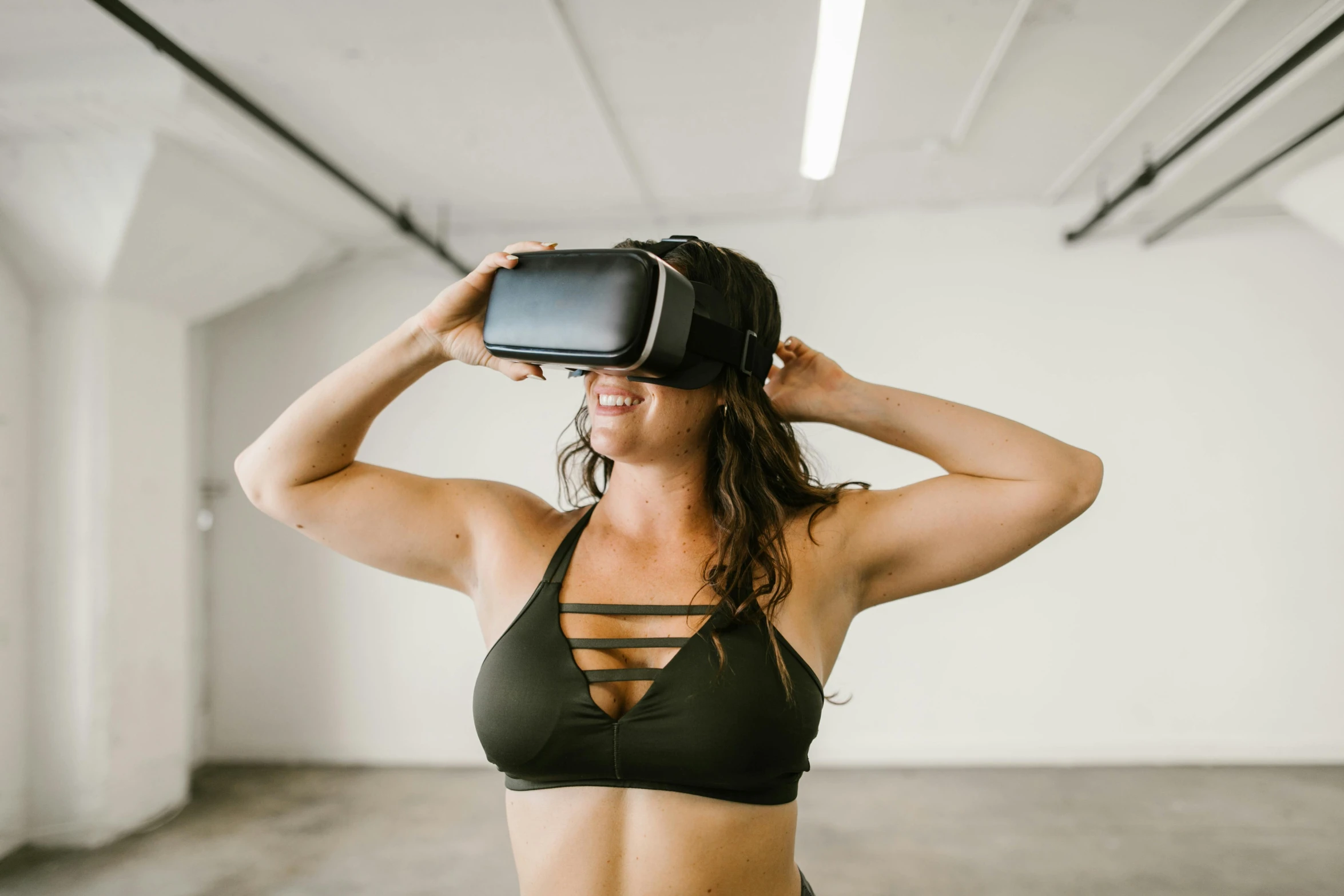 a girl wearing an off the shoulder black sports  top while using a virtual reality headset