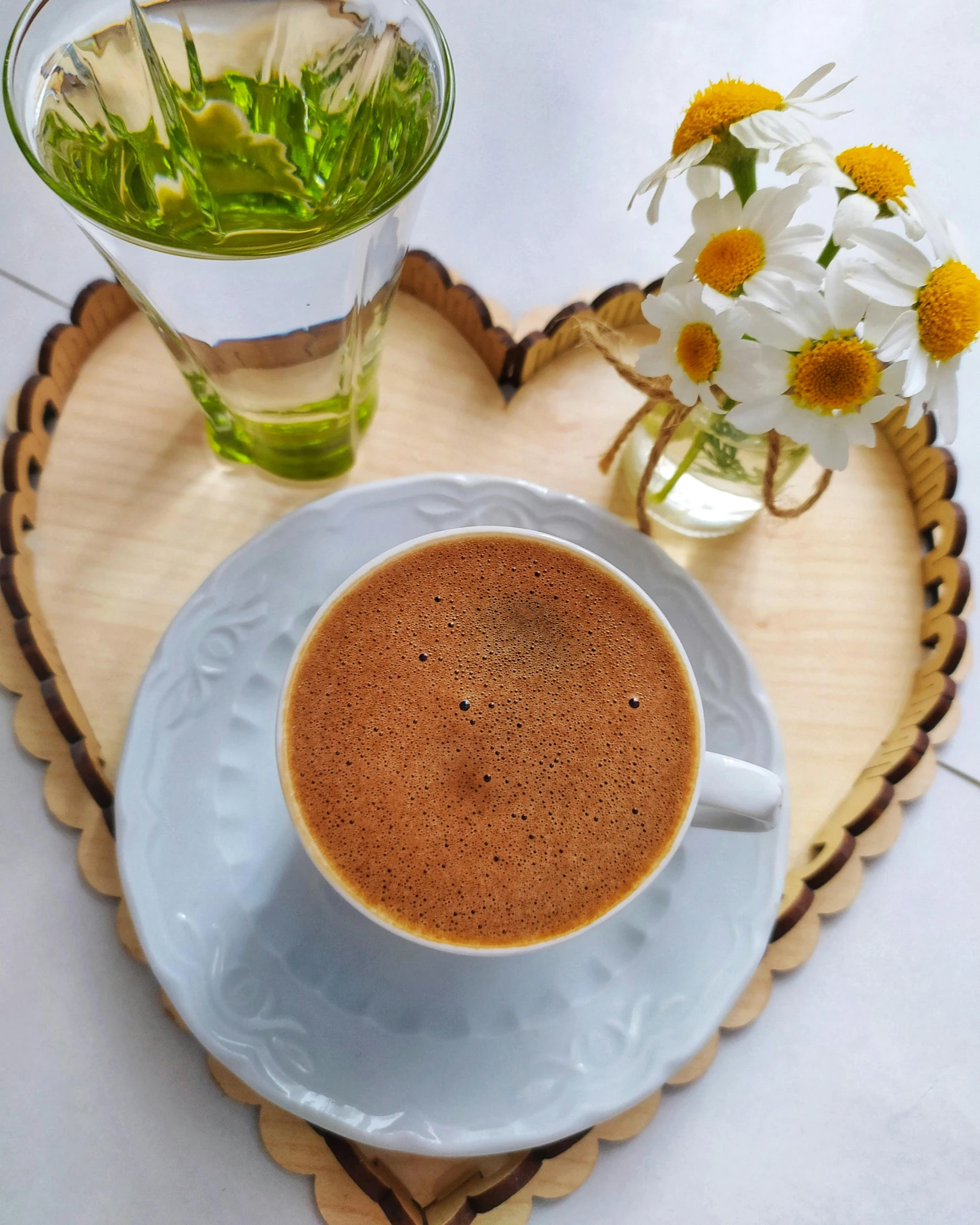 there is a cup of tea next to a vase with flowers