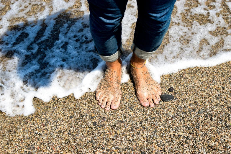 person standing on beach next to breaking wave