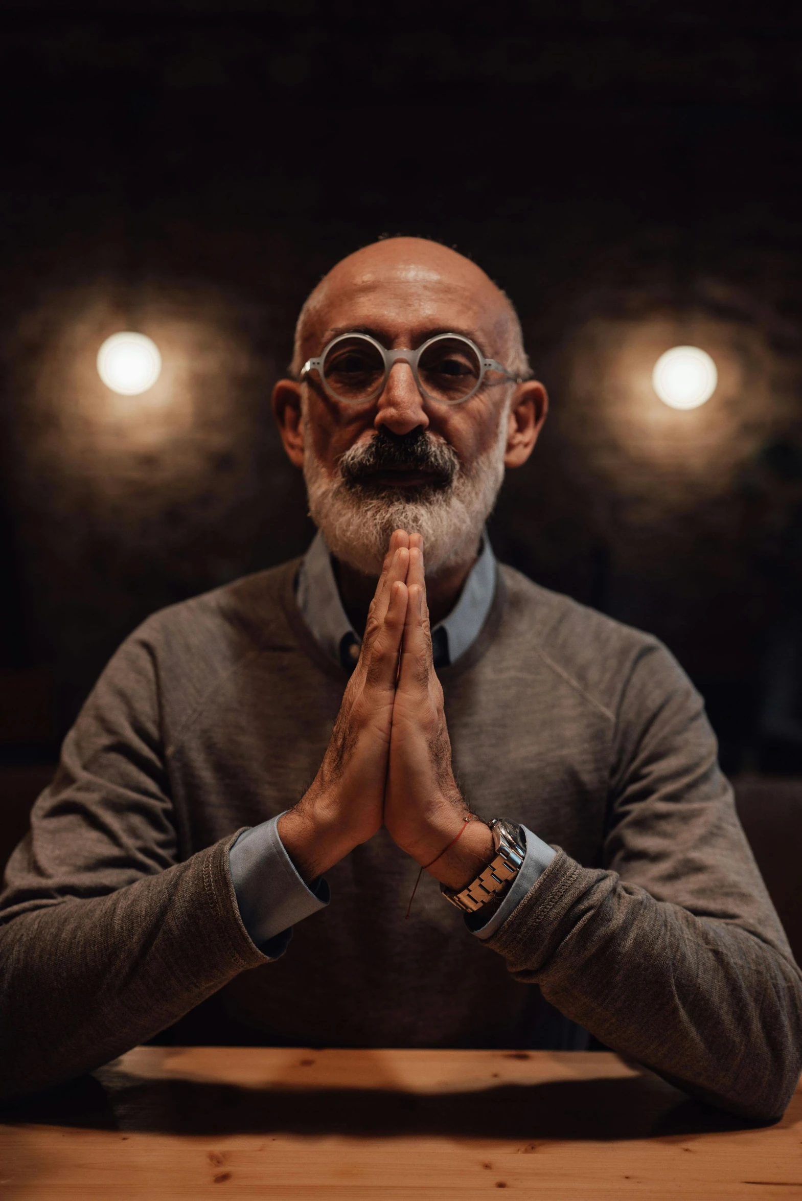 a man sitting at a wooden table with a light above him