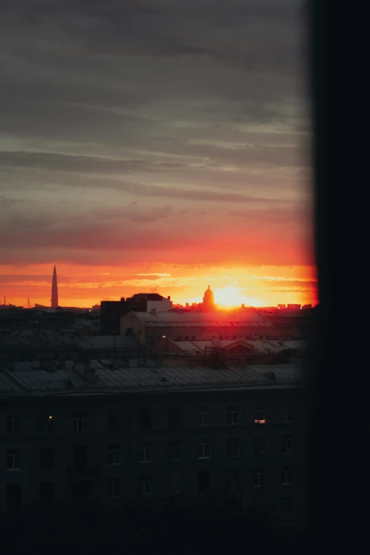 the sun rising in front of an overcast sky with a building in the foreground