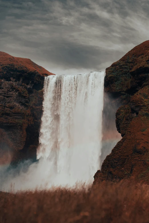 large waterfall on a cloudy day with brown grass