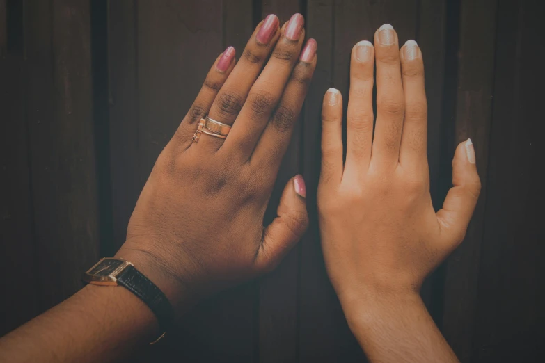 two woman hands reaching towards each other with their fingers together