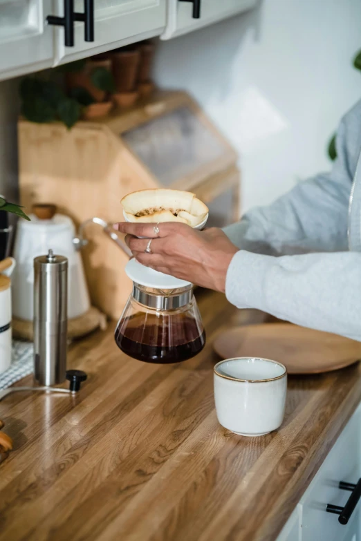 someone pouring a cup of coffee into a tea pot