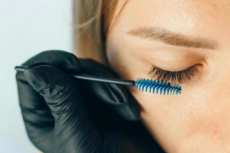 the closeup of a woman applying her lashes with a mascara brush