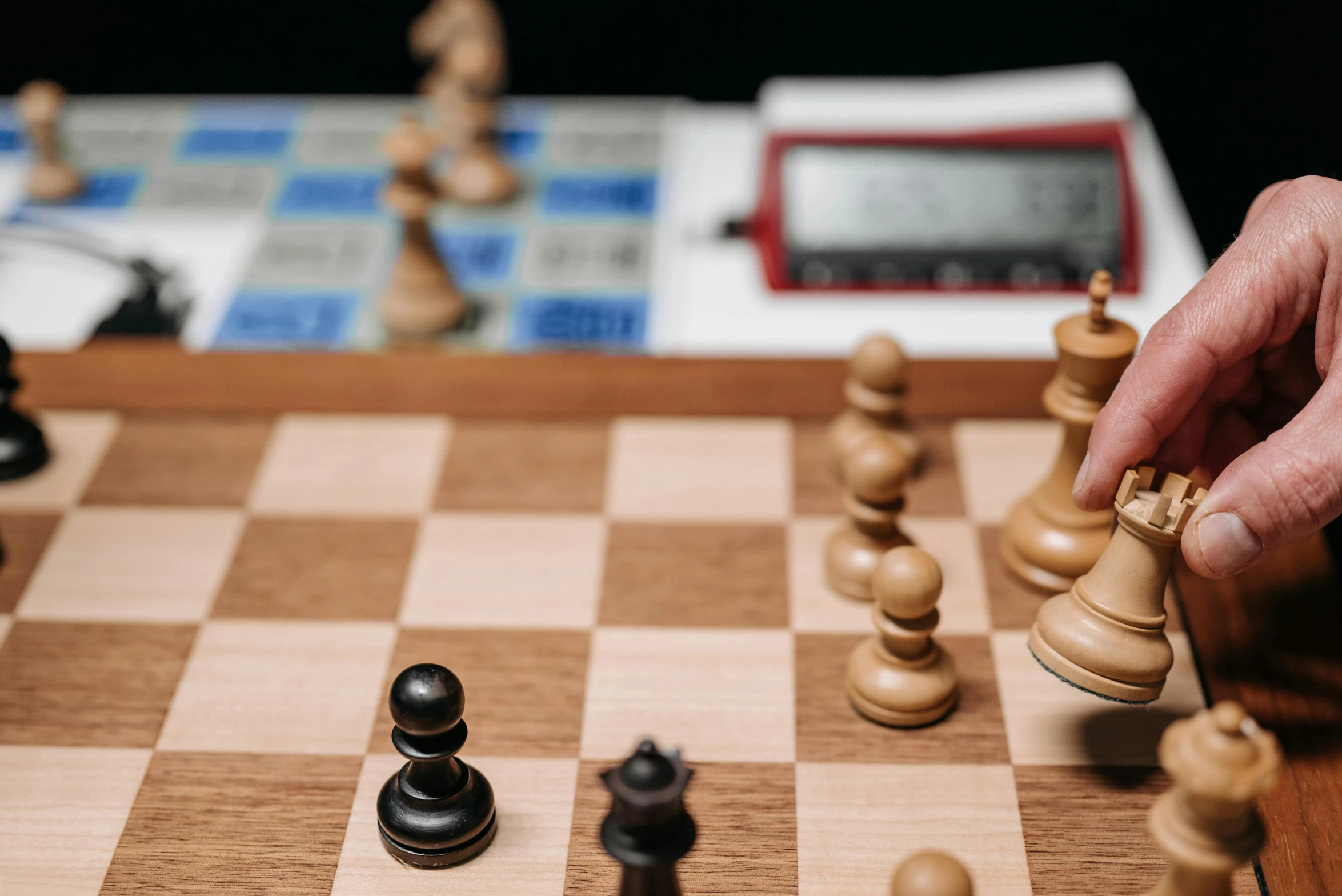 a hand moving chess pieces on top of a chess board