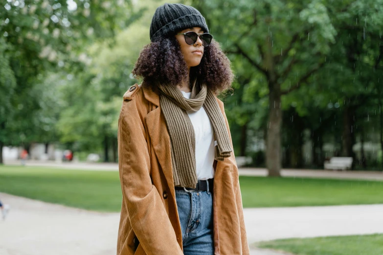 a woman walking in the rain wearing jeans, a sweater, and a hat