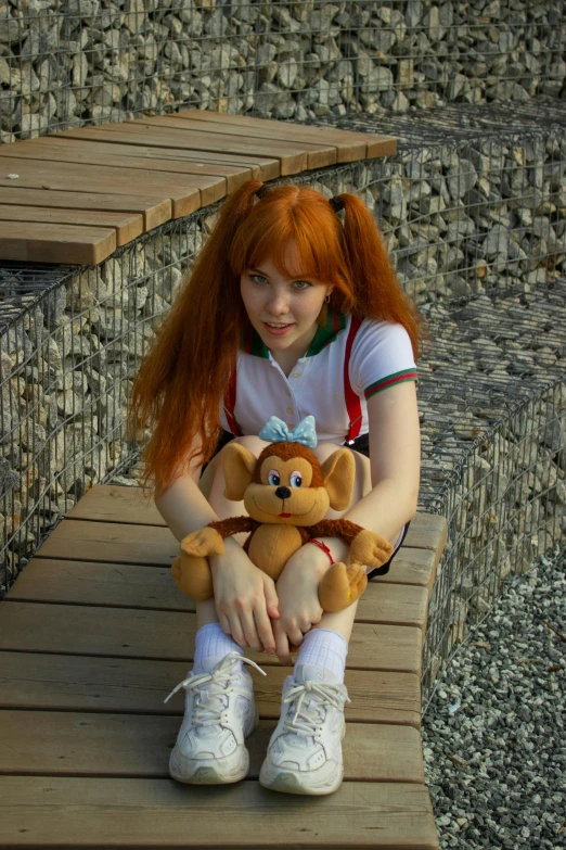 a young woman with red hair sits on a bench holding a stuffed animal