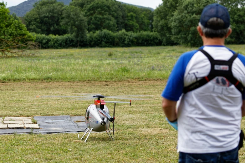 a man watches as a small helicopter flies low