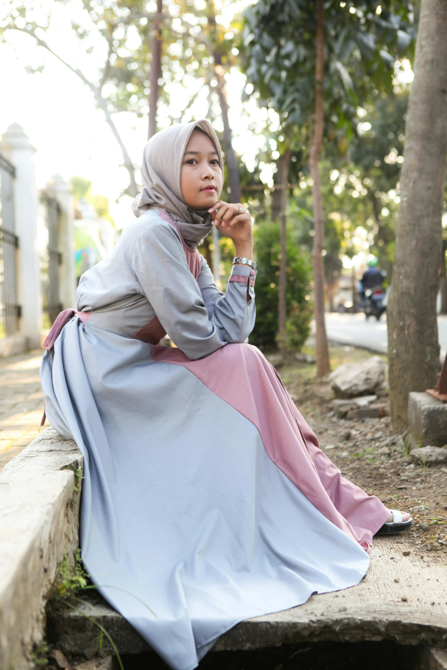 a woman wearing a dress sitting on a stone bench