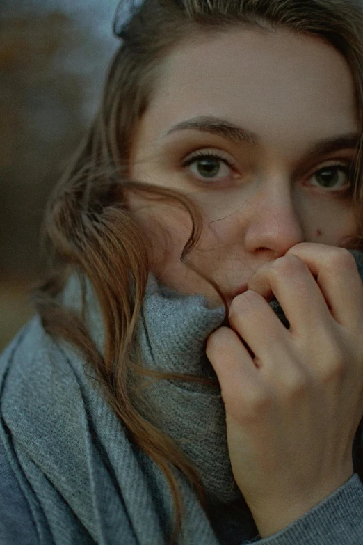 a woman with blonde hair in gray sweater rubbing her mouth