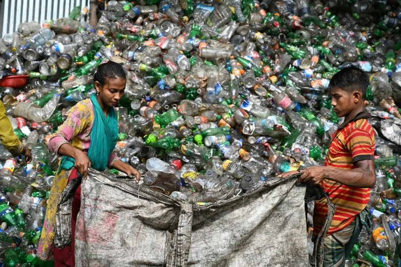 two men standing next to a giant amount of plastic bottles