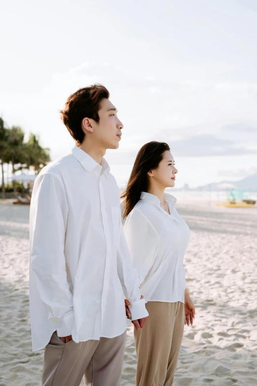 an asian couple posing for a po on a beach
