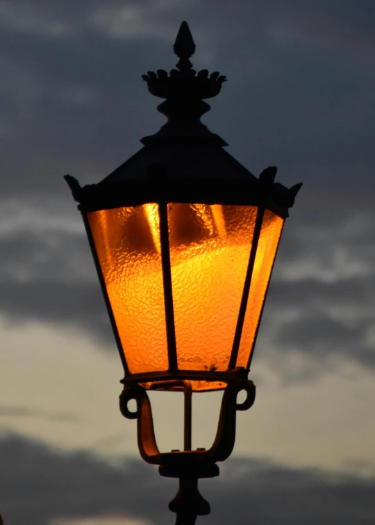 the top of an old fashioned street light at twilight