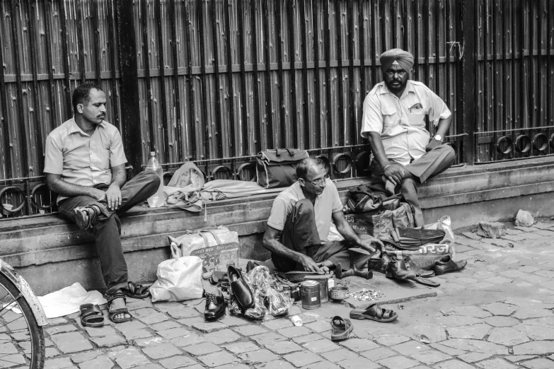 three men are sitting on the curb together