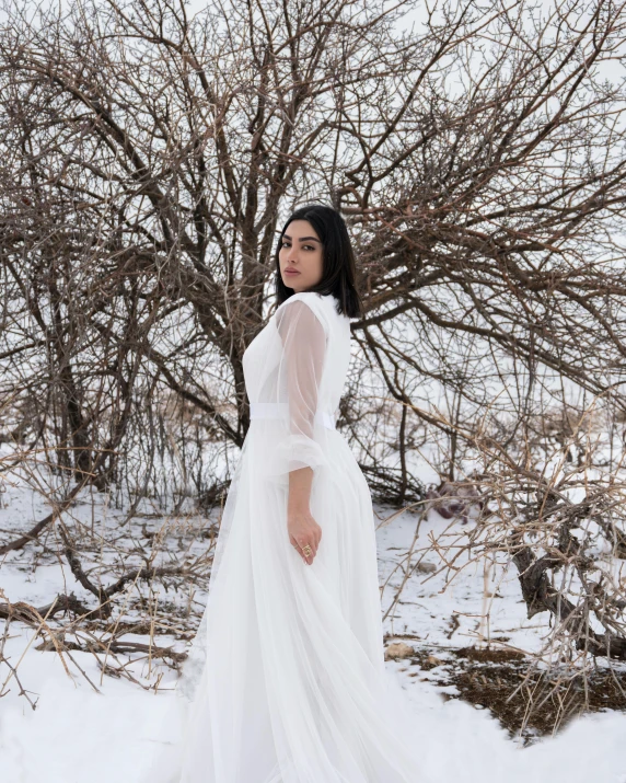 a woman is posing in front of a tree