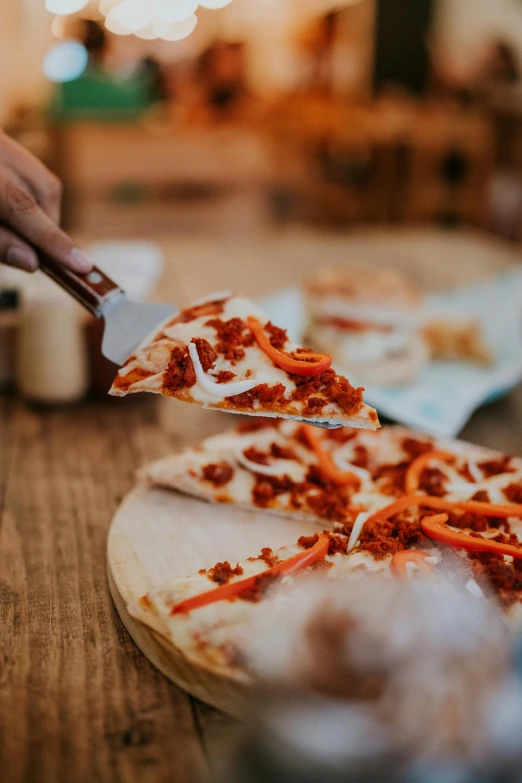 a person  a piece of pizza with a pizza cutter